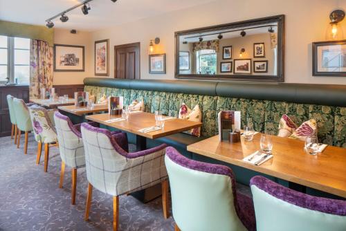 a restaurant with wooden tables and white chairs at The George Hotel, Amesbury, Wiltshire - The Coaching Inn Group in Amesbury