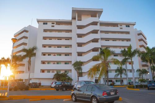 a large white building with cars parked in a parking lot at Hermoso en marina, asombrosas vistas by G P S rentas in Mazatlán