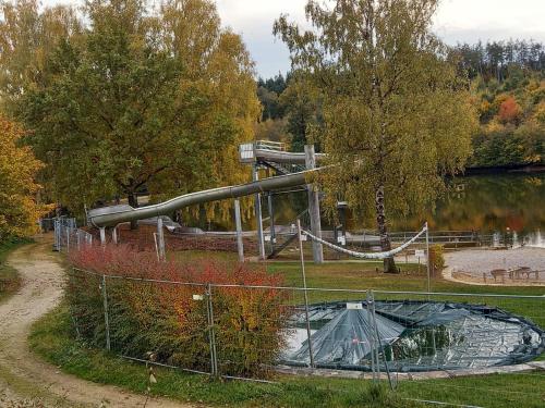 a slide in a park next to a lake at Tinyhouse Wemding in Wemding
