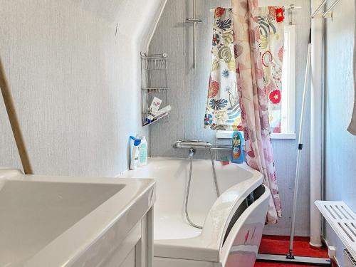 a white bathroom with a tub and a sink at Holiday home LYSVIK in Lysvik