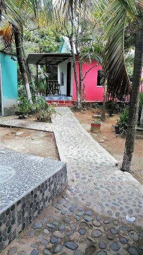a house with palm trees and a stone walkway at Hostal Recuerdos del Tayrona in El Zaino