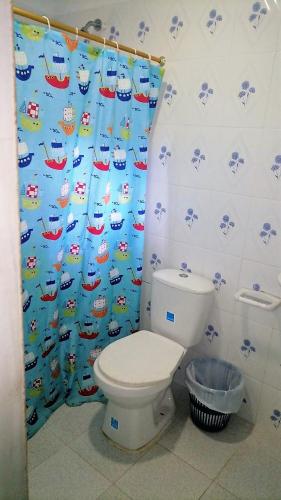 a bathroom with a toilet and a shower curtain at Hostal Recuerdos del Tayrona in El Zaino