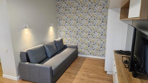 ein Sofa in einem Wohnzimmer mit einer Wand in der Unterkunft Modern Studio Apartment in Marijampolė