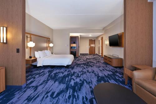 a hotel room with a bed and a flat screen tv at Fairfield by Marriott Inn & Suites Knoxville Airport Alcoa in Alcoa