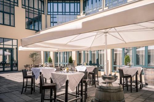 a restaurant with tables and chairs with white umbrellas at Munich Airport Marriott Hotel in Freising