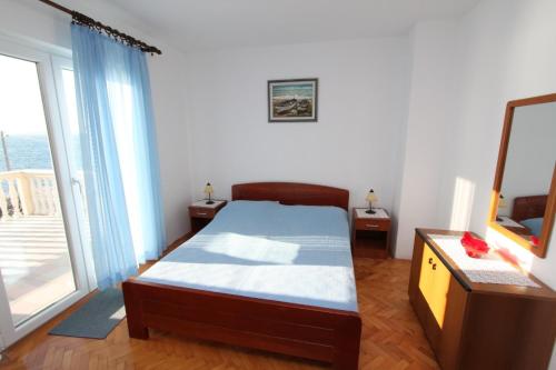 a bedroom with a bed and a tv and a window at Apartments Lunjski in Lun