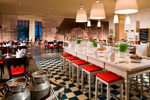 a restaurant with a long bar with red chairs at Munich Airport Marriott Hotel in Freising
