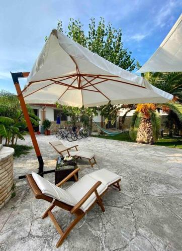 two chairs and an umbrella on a patio at Eleutheria beach villa by the beach in Torre Chianca