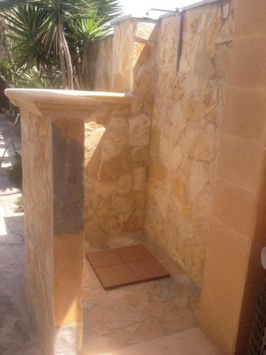 a bathroom with a stone wall with a toilet at Eleutheria beach villa by the beach in Torre Chianca