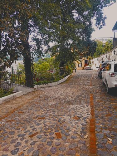 una calle adoquinada con un árbol y coches aparcados en Hotel El Mirador Anexo 1 en Santa Lucía Milpas Altas