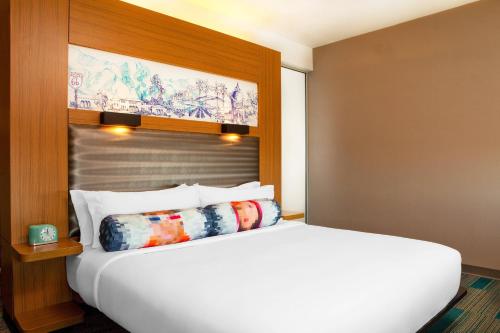 a bedroom with a white bed with a wooden headboard at Aloft Ontario-Rancho Cucamonga in Rancho Cucamonga