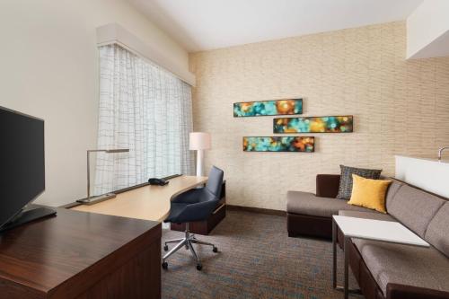 a hotel room with a desk and a couch and a living room at Residence Inn by Marriott Spartanburg Westgate in Spartanburg