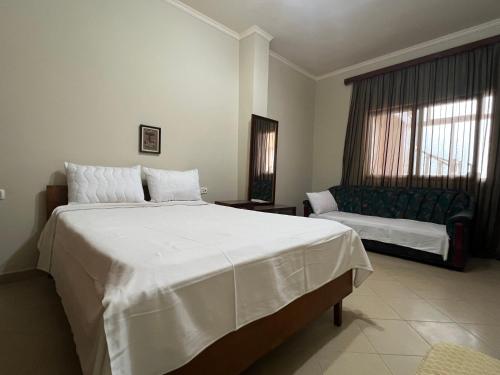 1 dormitorio con 1 cama blanca grande y 1 sofá en Guest House Vjosa en Përmet