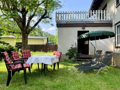 um grupo de cadeiras, uma mesa e um guarda-chuva em Wohnung mit Garten, Grill und Thermomix em Ühlingen-Birkendorf