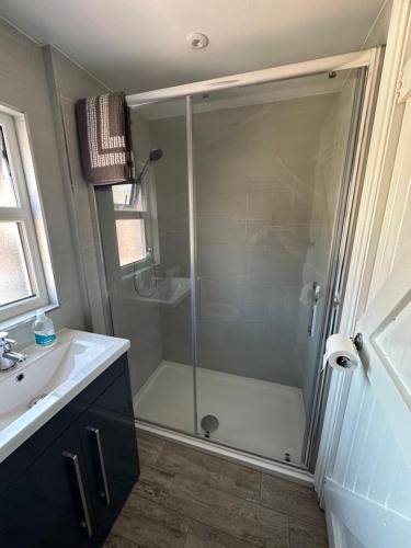 een badkamer met een douche en een witte wastafel bij Cottage, 10 mins Train / River in Burnham on Crouch