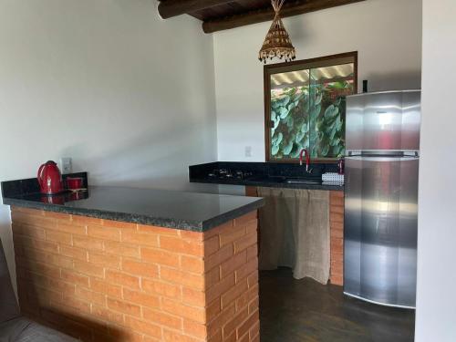 eine Küche mit einer Backsteintheke und einem Kühlschrank in der Unterkunft Lobo Guará Hospedagem Loft in Alto Paraíso de Goiás