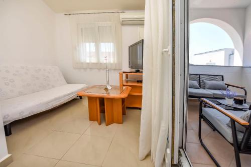 een woonkamer met een bed en een tafel met een tv bij Apartments Antea in Rogoznica