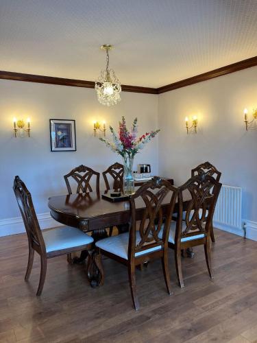 a dining room table with chairs and a vase of flowers at The Riviera Hotel & Apartments - Alum Chine in Bournemouth