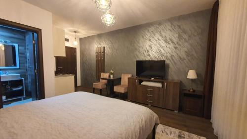 een slaapkamer met een bed en een televisie en een tafel bij IRIS Apartments in Bitola