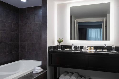a bathroom with a tub and two sinks and a mirror at The Baronette Renaissance Detroit-Novi Hotel in Novi