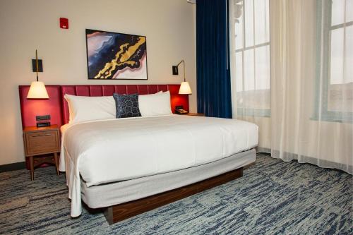 a bedroom with a large bed with a red headboard at BLU-Tique, Akron, a Tribute Portfolio Hotel in Akron
