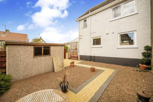 a backyard of a white house with a courtyard at Beautiful three bedroom seaside retreat in Prestonpans
