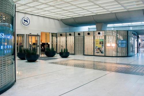 a lobby of a building with potted plants at Sheraton Paris Charles de Gaulle Airport Hotel in Roissy-en-France