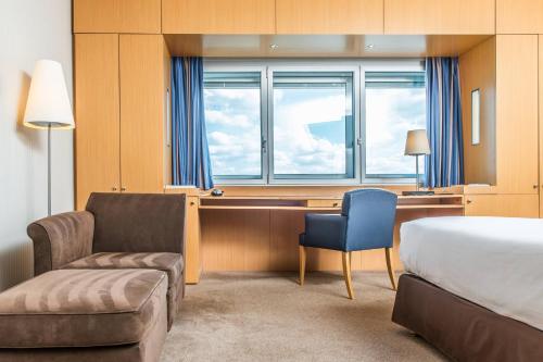 a hotel room with a desk and a bed and a chair at Sheraton Paris Charles de Gaulle Airport Hotel in Roissy-en-France