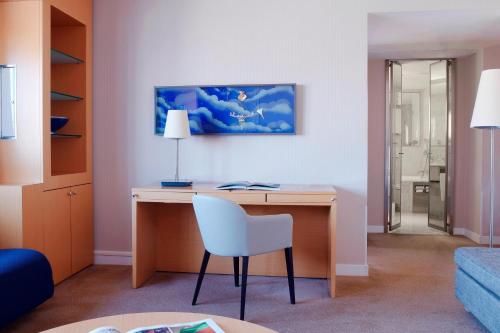 a room with a desk with a white chair at Sheraton Paris Charles de Gaulle Airport Hotel in Roissy-en-France