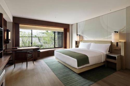 a bedroom with a bed and a desk and a window at HOTEL THE MITSUI KYOTO, a Luxury Collection Hotel & Spa in Kyoto