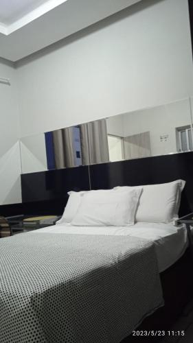 uma cama com lençóis brancos e almofadas num quarto em Hospedaria FOR755 em Fortaleza