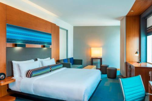 a bedroom with a large white bed and chairs at Aloft Abu Dhabi in Abu Dhabi