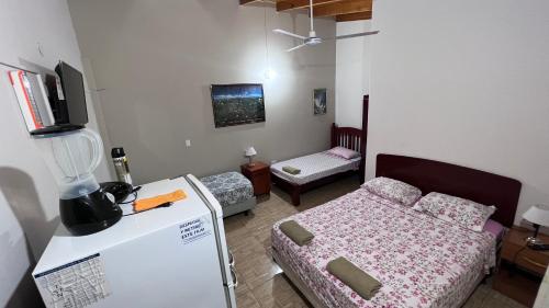 Una pequeña habitación con una cama y una nevera. en Apart Nicolas, en Puerto Iguazú