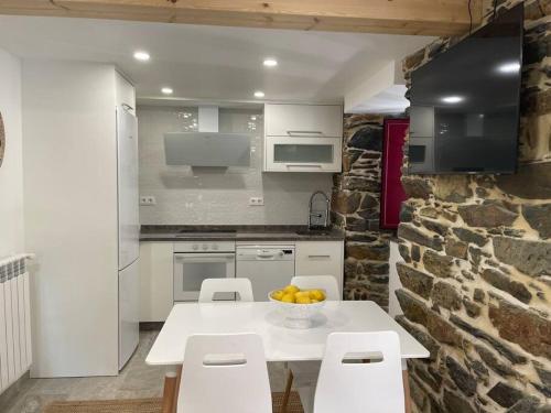 a kitchen with a table and chairs and a stone wall at Moderno apartamento con jardín in Santa María La Mayor del Rosario