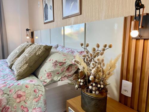 a bedroom with a bed and a vase with flowers at Hotel APART Zuccolotto 101 in Aracruz