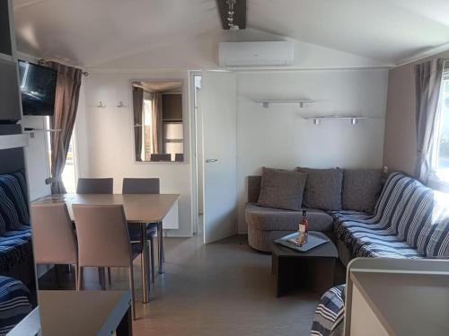 un salon et une cuisine avec un canapé et une table dans l'établissement Mobil-Home FO 30 à Vias - La Carabasse - Camping Siblu avec piscine, à Vias