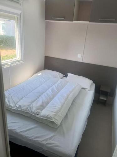 un lit blanc dans une chambre avec une fenêtre dans l'établissement Mobil-Home FO 30 à Vias - La Carabasse - Camping Siblu avec piscine, à Vias