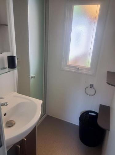 une salle de bain blanche avec un lavabo et une fenêtre dans l'établissement Mobil-Home FO 30 à Vias - La Carabasse - Camping Siblu avec piscine, à Vias