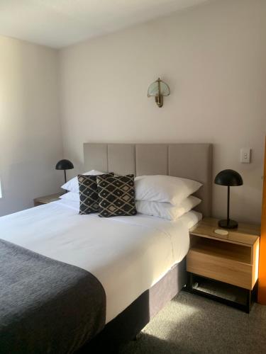 1 dormitorio con 1 cama blanca grande y 2 lámparas en Apex Motorlodge en Nelson