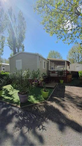 une maison avec trois plantes en pot dans une cour dans l'établissement Mobil-Home MA 20 à Vias - La Carabasse - Camping Siblu avec piscine, à Vias