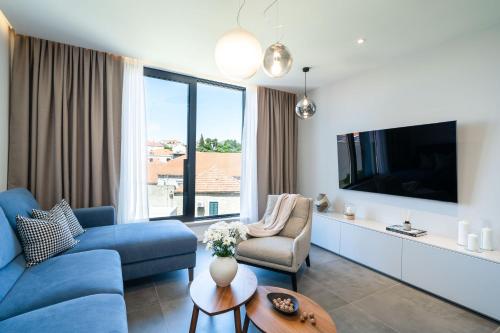 salon z niebieską kanapą i telewizorem w obiekcie Olea Suite w mieście Cavtat