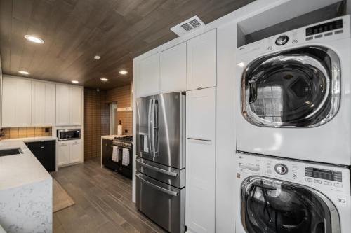 a kitchen with a refrigerator and a washer and dryer at Sunset House - Luxury Pool and Hot Tub Retreat in Dallas