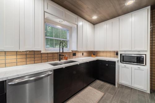 a kitchen with white cabinets and a sink and a microwave at Sunset House - Luxury Pool and Hot Tub Retreat in Dallas