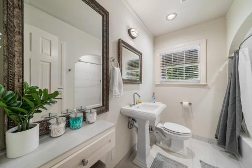 a bathroom with a sink and a toilet and a mirror at Sunset House - Luxury Pool and Hot Tub Retreat in Dallas
