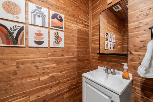 a bathroom with a white sink and wooden walls at Sunset House - Luxury Pool and Hot Tub Retreat in Dallas