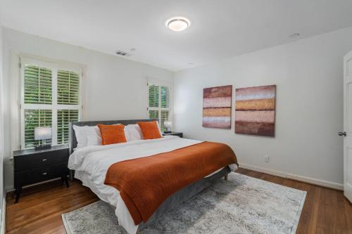 a white bedroom with a large bed with orange pillows at Sunset House - Luxury Pool and Hot Tub Retreat in Dallas