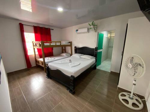 a bedroom with two bunk beds and a fan at Hostal Recuerdos del Tayrona in El Zaino