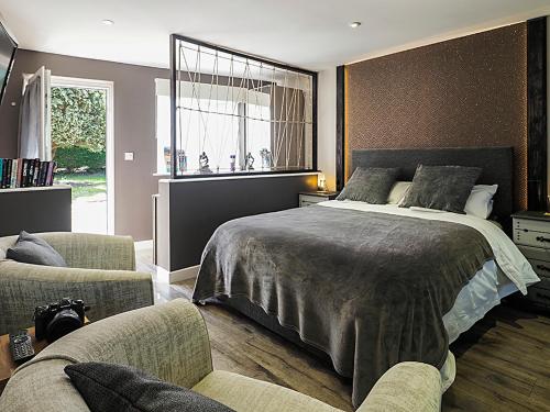 een slaapkamer met een bed en 2 stoelen en een raam bij Beautiful studio apartment near the Norfolk Broads in Rackheath