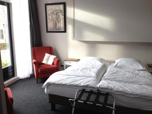 een slaapkamer met een bed en een rode stoel bij De Rede in Molkwerum