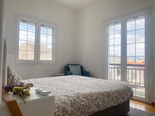 a bedroom with a bed and a chair and windows at Hellenic Pleasure Residences in Athens